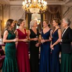 Groupe élégant de femmes portant des tenues de soirée variées dans un intérieur luxueux et raffiné.